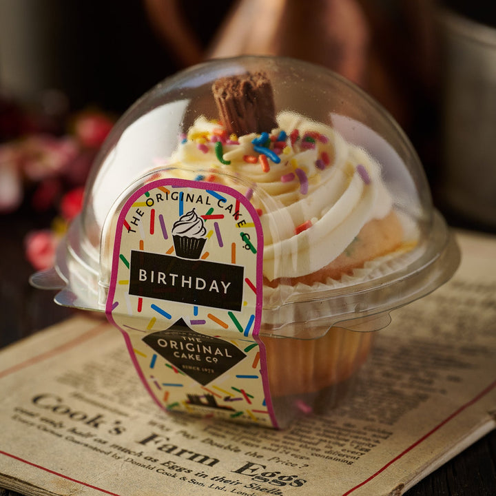 Box of 6 vanilla birthday cupcakes topped with rich frosting and a small flake.






