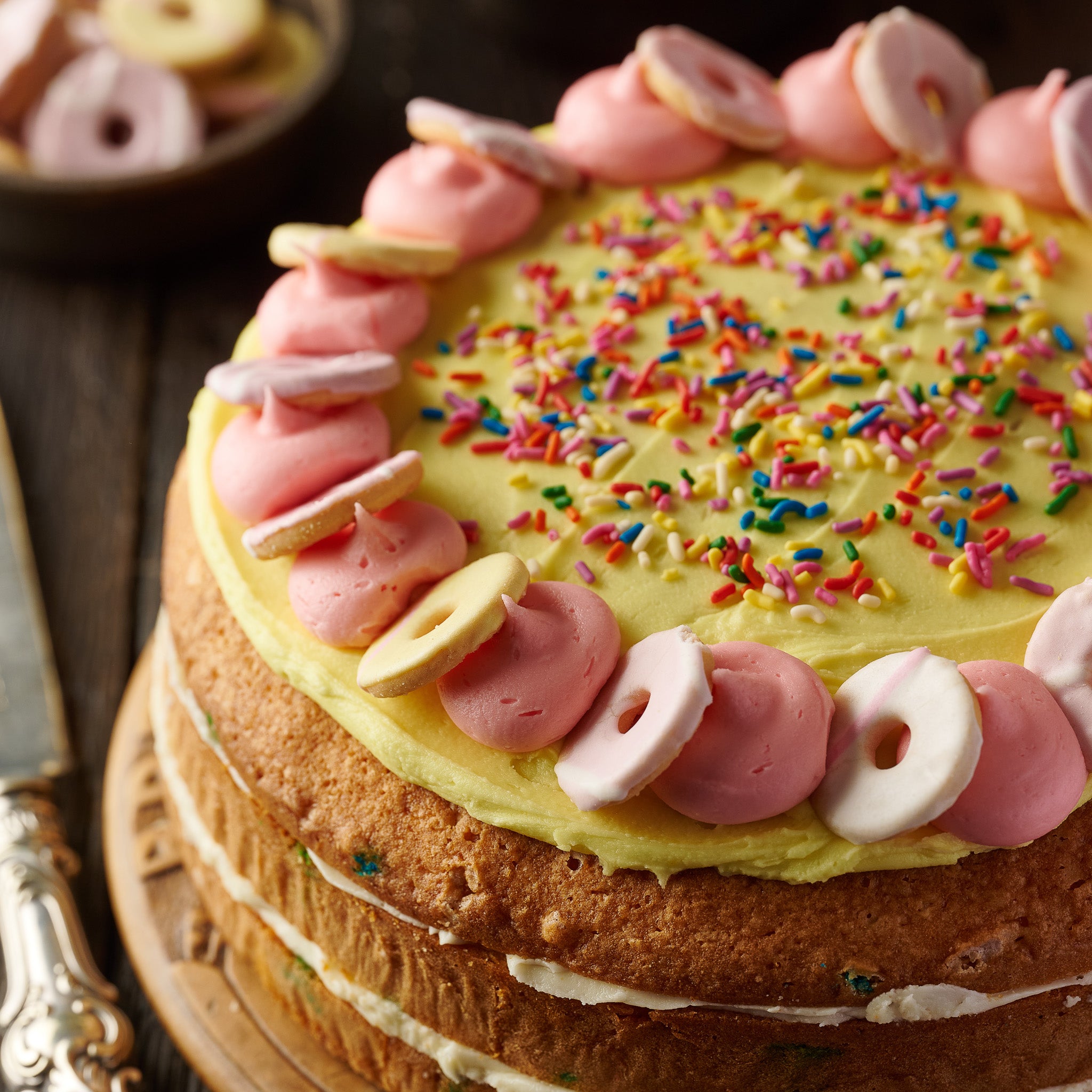 Old-school vanilla cake with colourful sprinkles, topped with party ring biscuits and creamy frosting, perfect for birthday parties, special celebrations, wholesale, and cafés